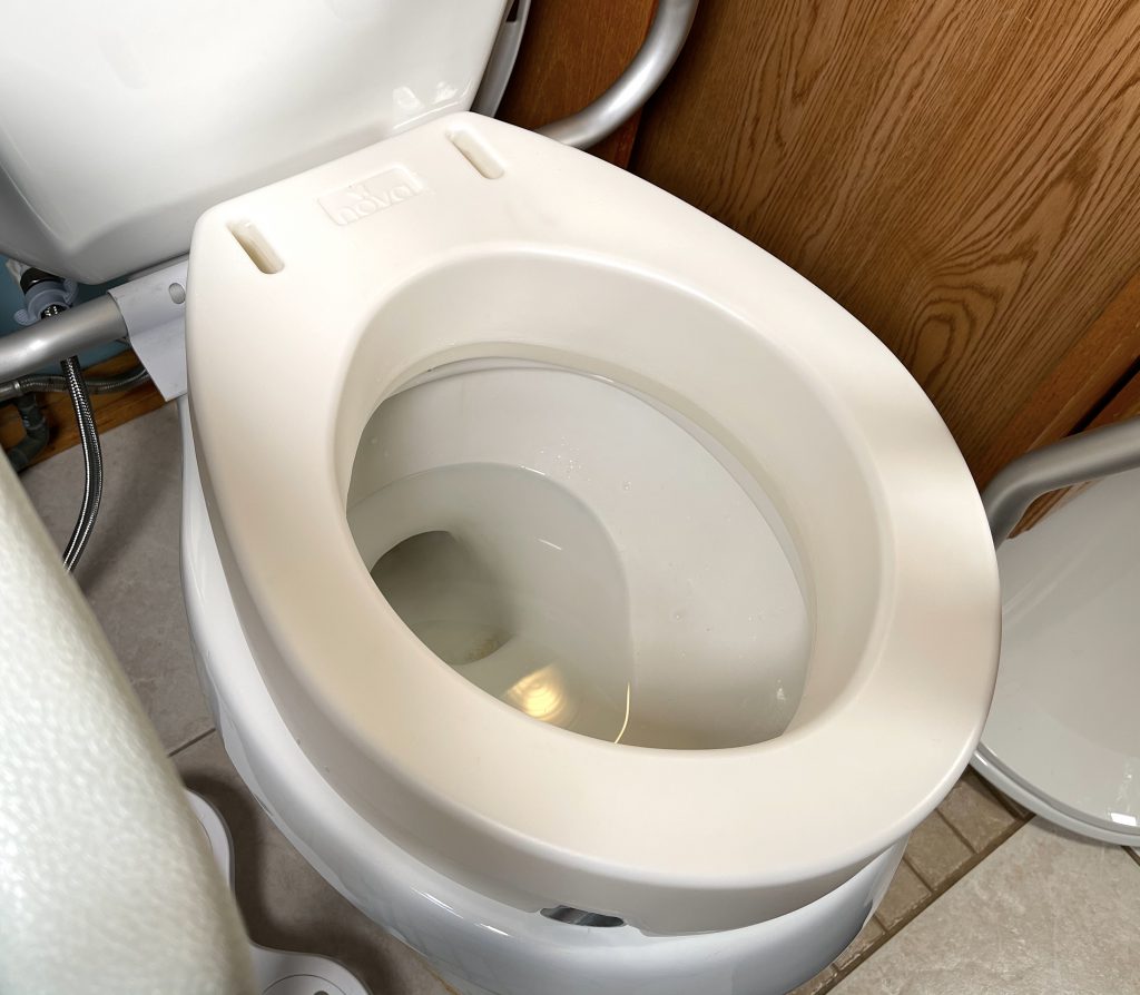 Raised toilet seat place on toilet safety rails