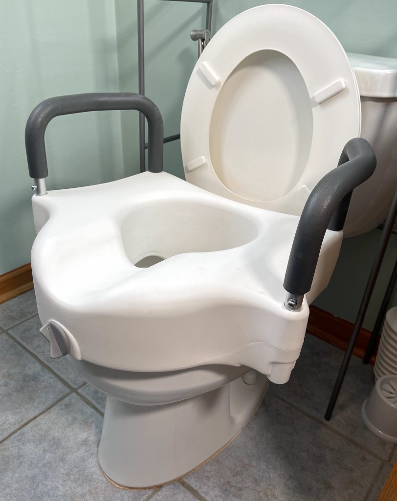 Clamp-on raised toilet seat front of riser placed into position inside bowl