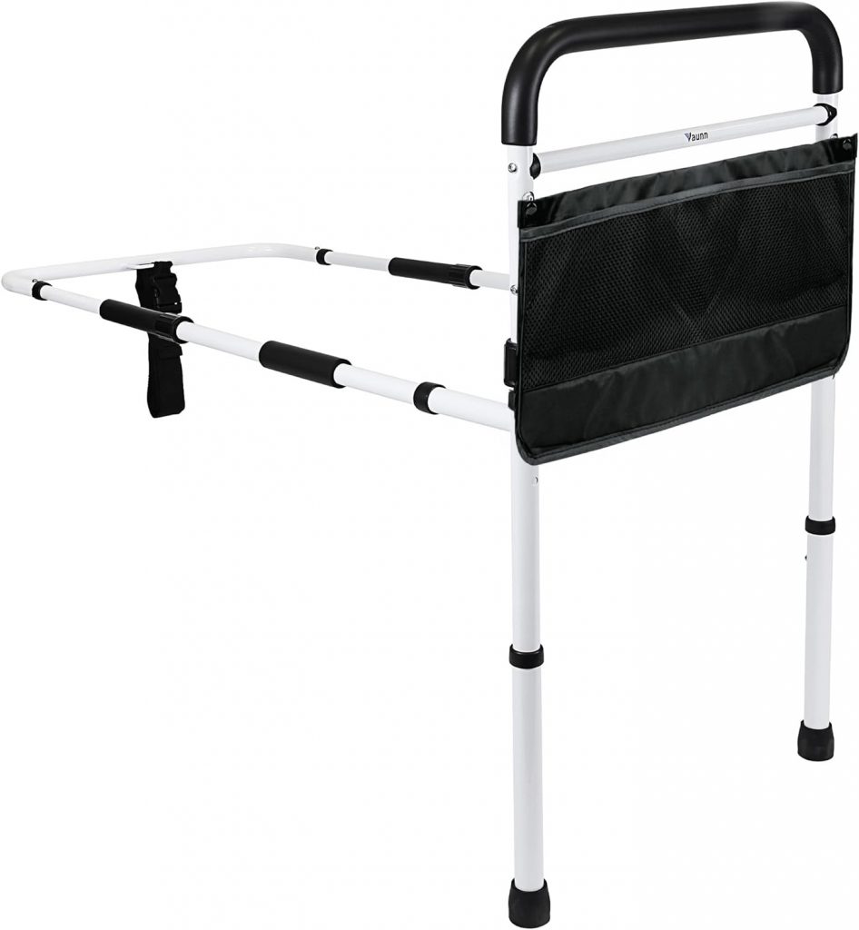 Adjustable white bed assist rail with a black padded handle, non-slip foam grips, and an attached black mesh storage pouch. The rail features a safety strap for secure attachment to the bed frame and height-adjustable legs with rubber tips for stability. How to Sleep After Back Surgery - EquipMeOT